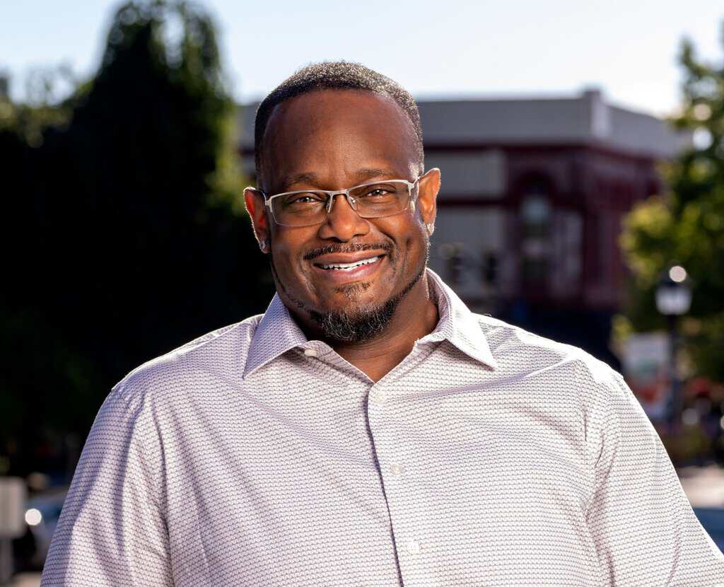 Titonian Wallace Sr. headshot. Smiling and standing outside with a building in the background.